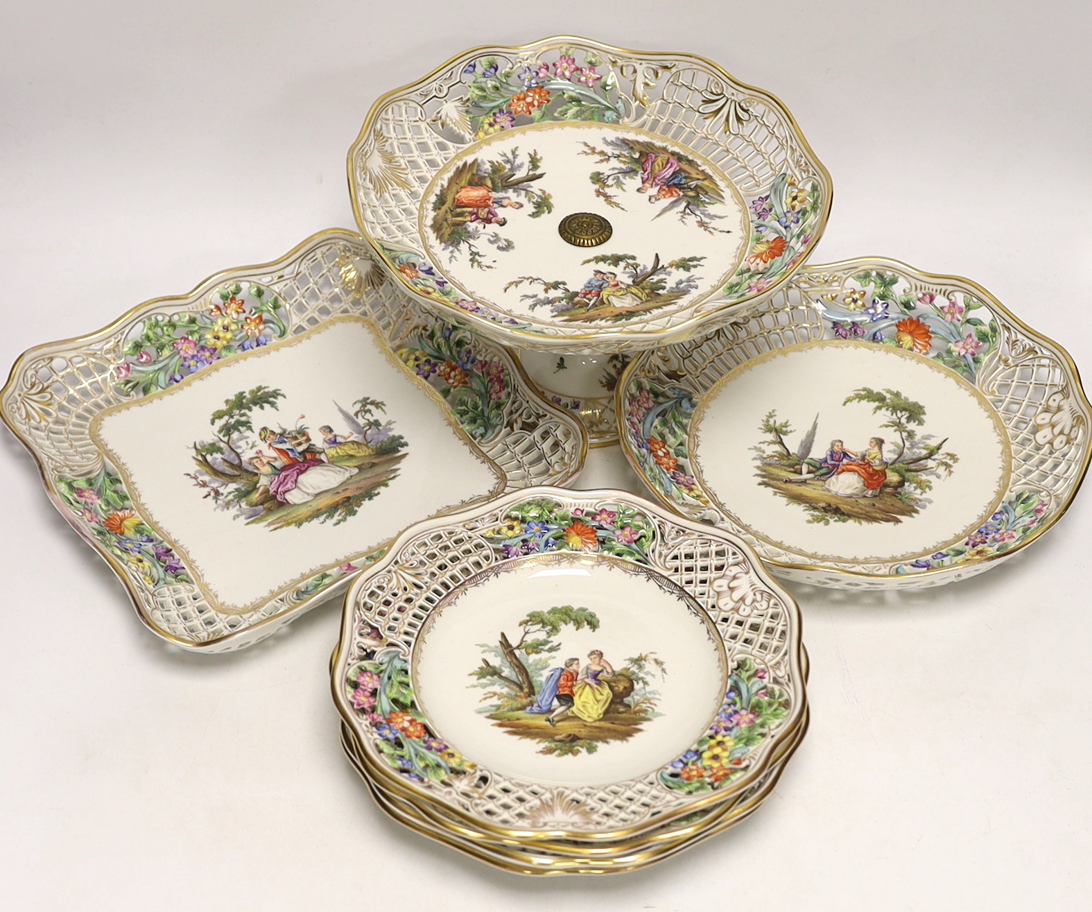 A Dresden Meissen style part dessert set, painted with courting couples in the landscape, consisting of a comport two dishes and four plates, comport 15.5cm high